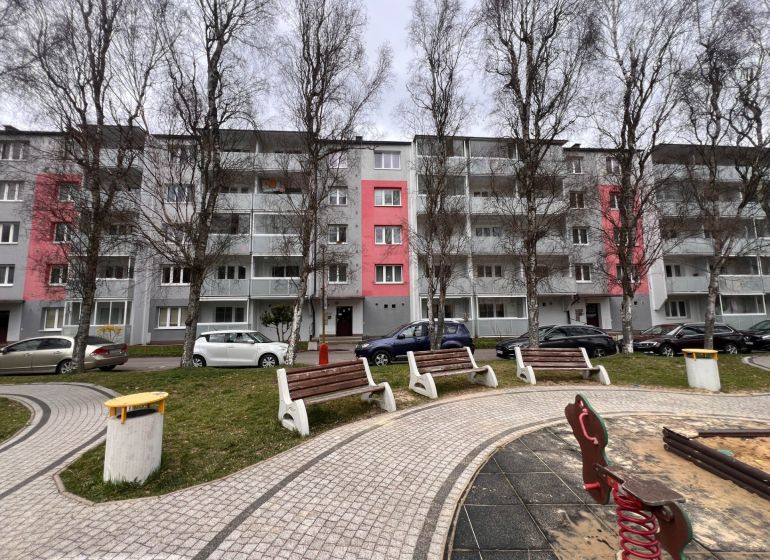 An apartment building in Ružomberok with trees and parking spaces in front of the two-room apartments.