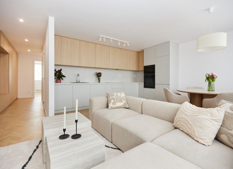 A spacious living room in a 4-room apartment with a kitchenette and a floor with a wooden decor.