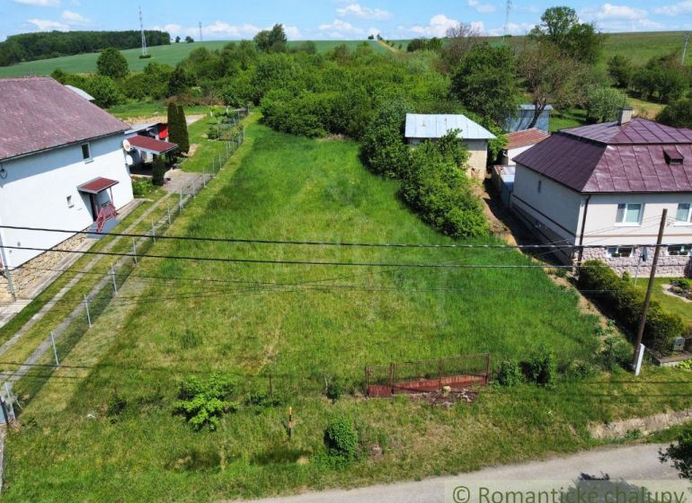 A plot for residential use in Karna, bordered by neighboring houses and greenery.