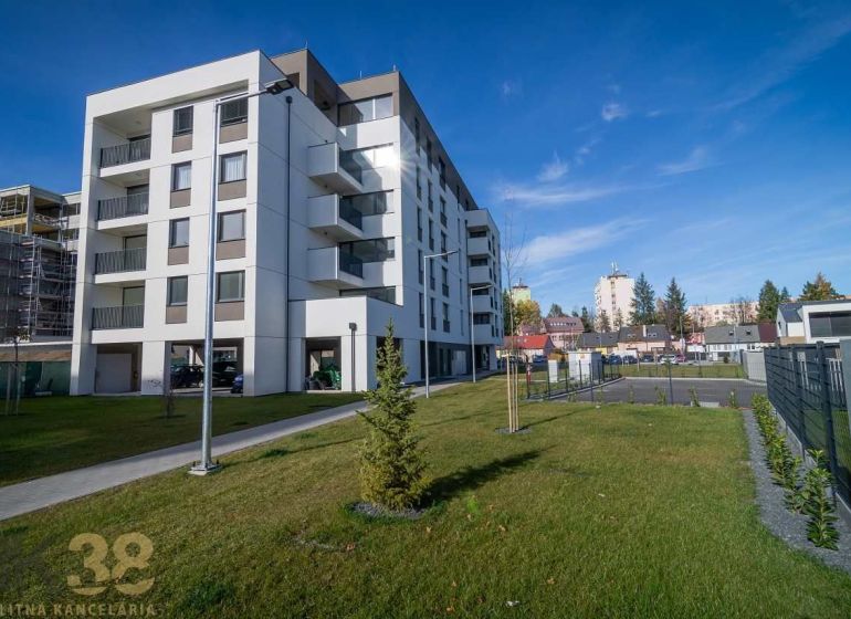 An apartment building in Poprad with a green lawn and neighboring buildings in the background.