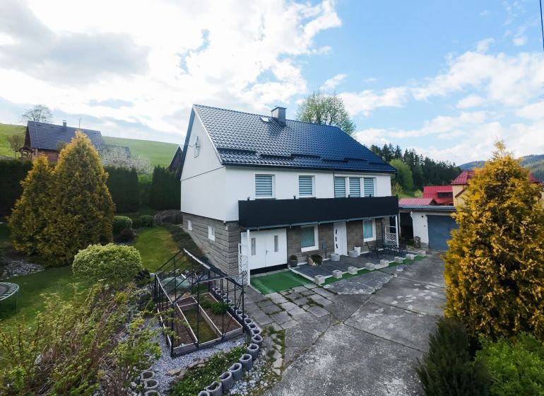 A family house in Makov surrounded by a well-maintained garden with a greenhouse and paved paths.