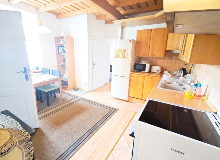 A kitchen in a 2-room apartment with a wooden decor floor and a wooden ceiling.