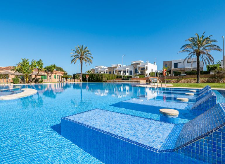 A swimming pool at a holiday apartment in Cala Murada, Mallorca, with palm trees and loungers.