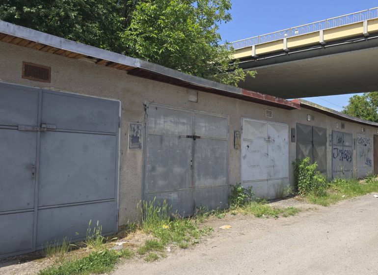 Garages on Jesenského Street in Zvolen along the road with greenery and graffiti.