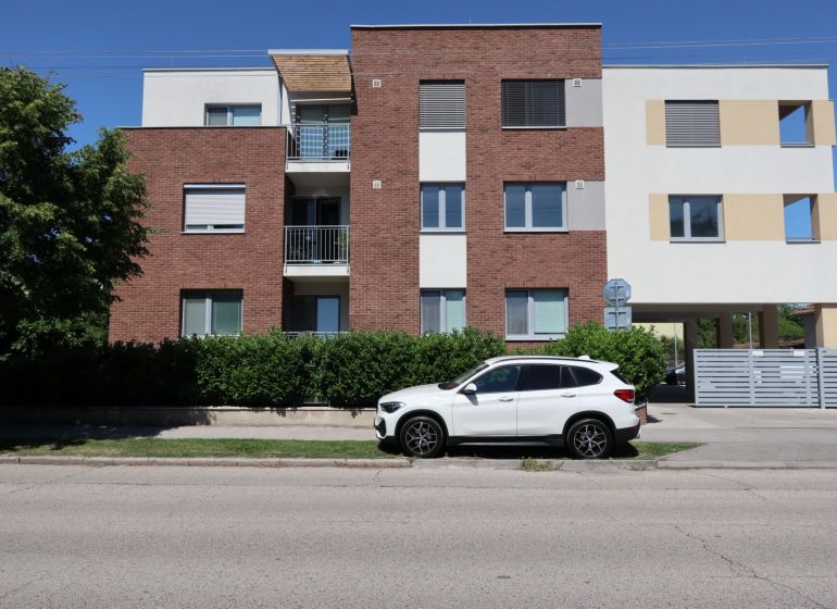 An apartment building on Štefánikova Street in Dunajská Streda with a white car in the foreground.