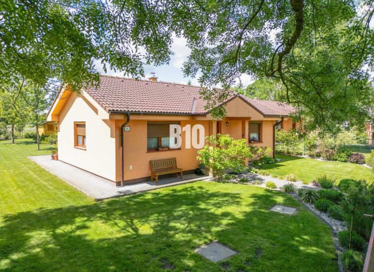 A family house in Bíľkovy Humence surrounded by a well-maintained garden and green lawn.