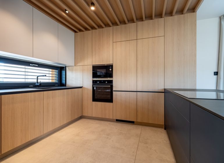 A kitchen in a family house with wooden cabinets and a black countertop.