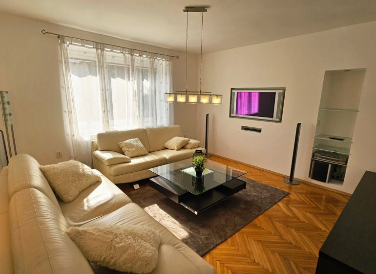 Living room with a white sofa and a wooden decor floor in a 2-room apartment.