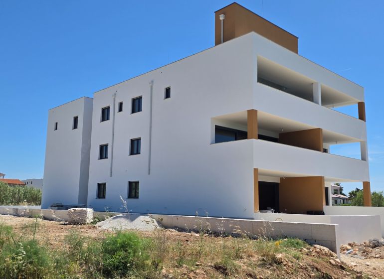 White apartment building with balconies in Privlaka against the blue sky, 3-room apartment.