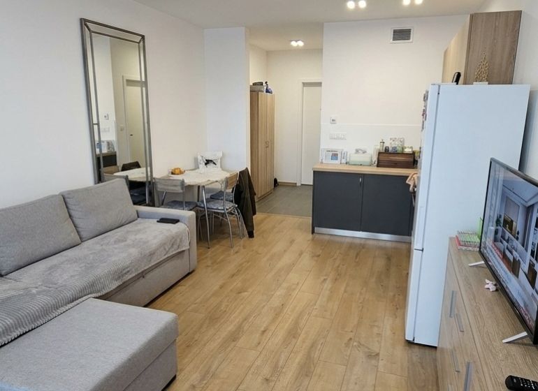 Living room in a one-room apartment with a corner sofa and a floor with a wooden decor.
