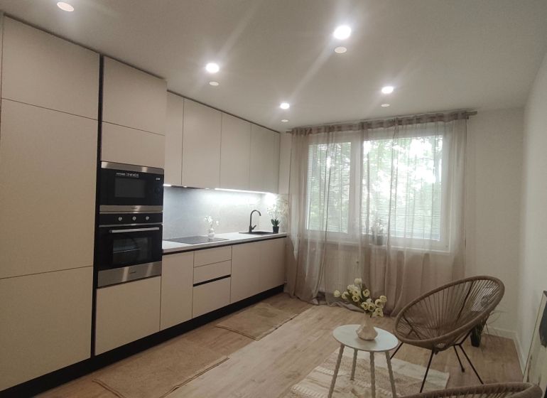 Kitchen in a 4-room apartment with a wooden decor floor and a large window.