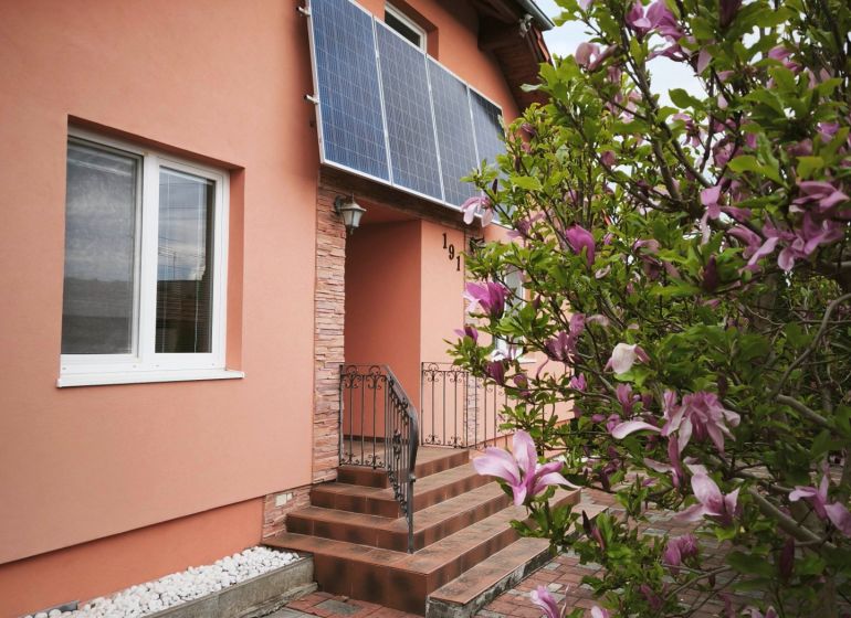 A family house on Hlavná Street in Martin nad Žitavou with solar panels and a magnolia.