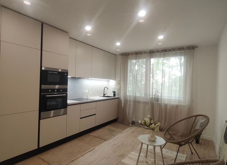 A minimalist kitchen in a 4-room apartment with integrated appliances and a window with a view.