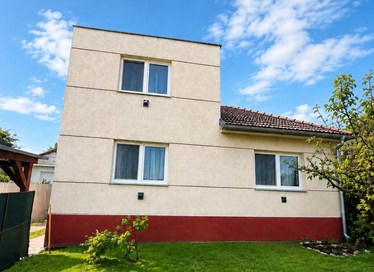 A family house in Šalgovce with a well-maintained lawn under a blue sky.