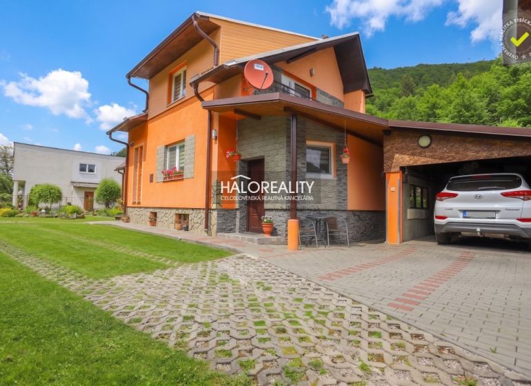 A family house in Dolná Mariková with a garage, lawn, and parking area in front of the house.