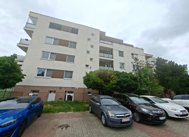 Apartment building on Športová Street in Dunajská Lužná with a parking lot and cars in front of the building.