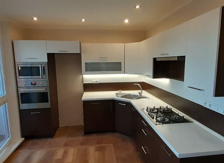 A kitchen in a 2-room apartment with a wood-decor floor and built-in appliances.