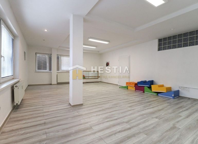 Spacious commercial spaces with wood-patterned flooring and colorful seating elements.