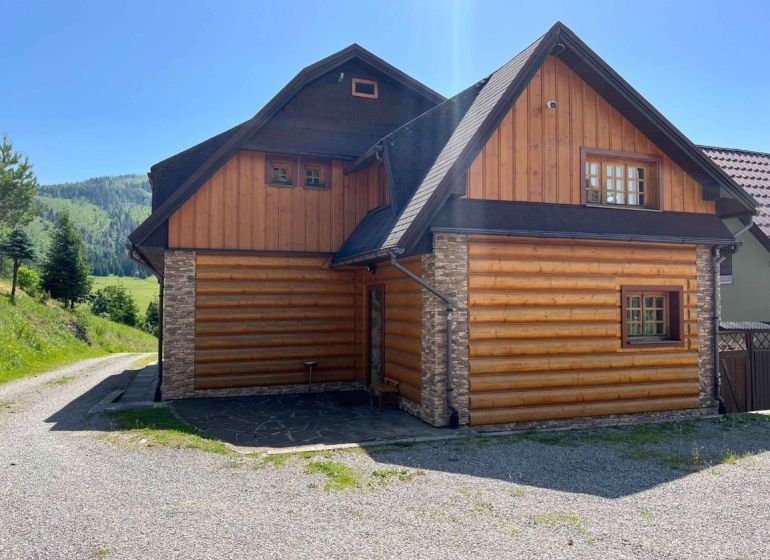 A family house in Veľké Borové with a wood and stone-clad exterior near the forest.