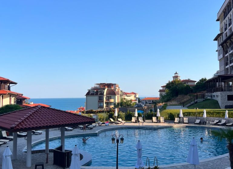 A view of the pool with surroundings and the sea in the town of Sveti Vlas, surrounded by sunbeds.