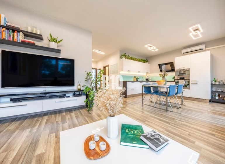 Living area with kitchen, wooden decor flooring, and modern furniture in a 3-room apartment.