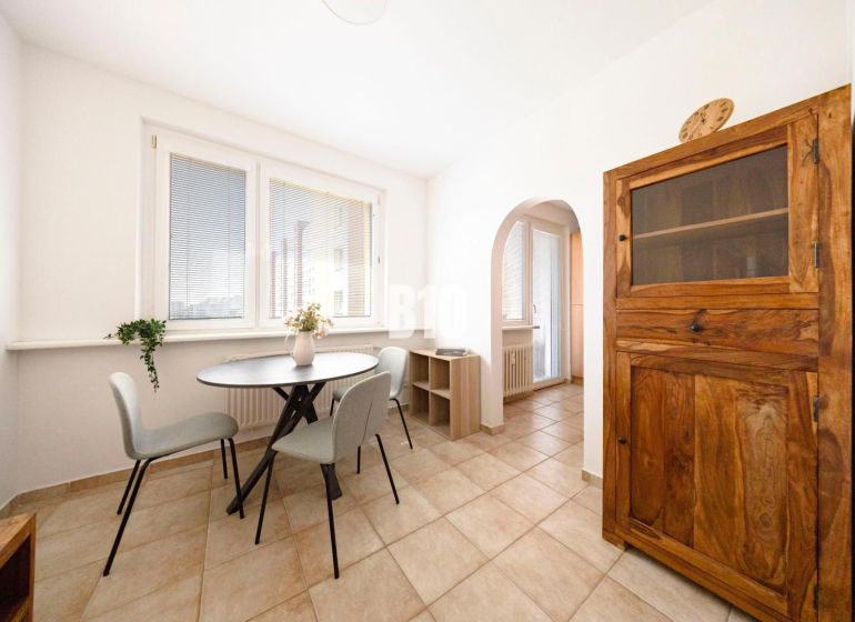 Dining area with a table, chairs, and a wooden cabinet in a 3-room apartment.