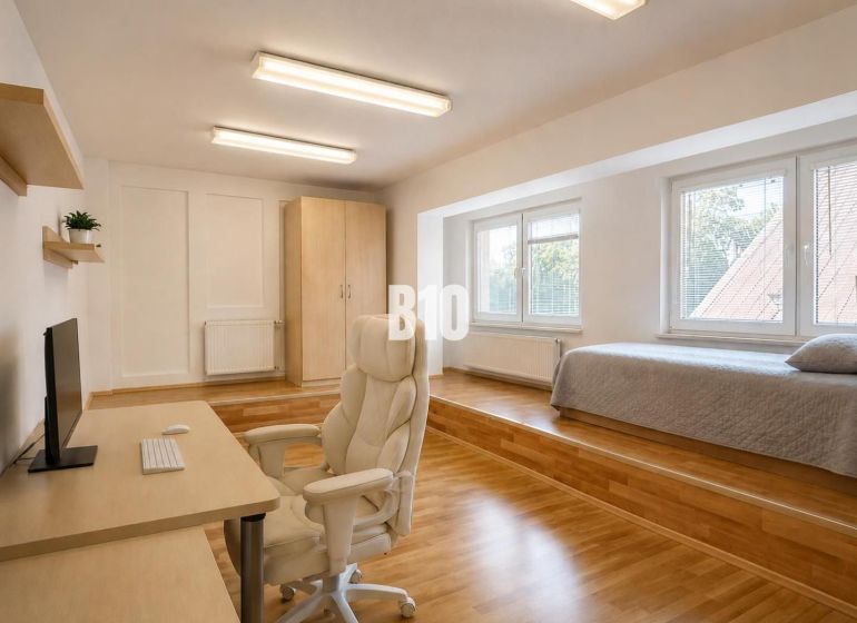 A spacious room in a 2-room apartment with a computer desk and a bed on an elevated floor.