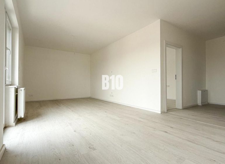 Spacious bright interior with wood-decor flooring in a 2-room apartment.