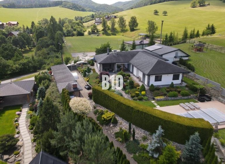 A family house in Súľov-Hradná with an ornamental garden and a view of the surrounding hills.