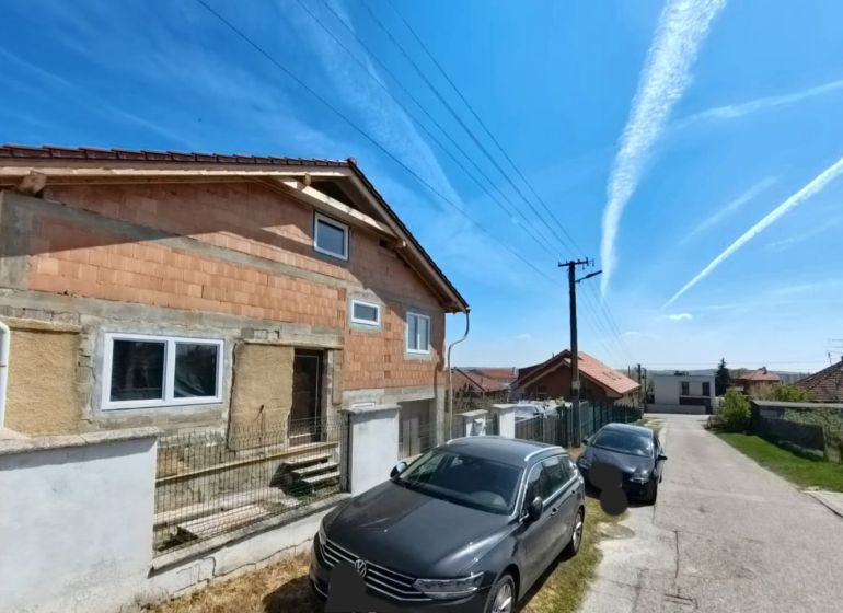 A family house at Lehárova 2 in Nitrianske Hrnčiarovce with parked cars and a blue sky.
