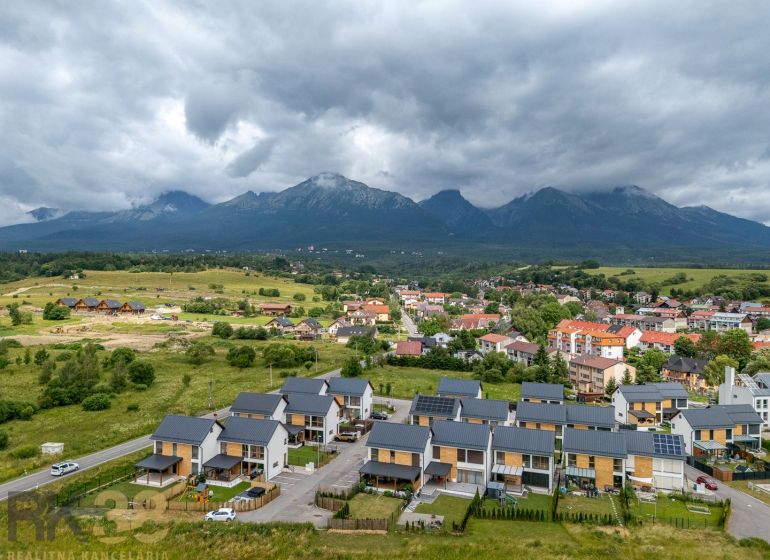 Nová Lesná, Vodárenská Street with a view of the mountains with new buildings and clouds.