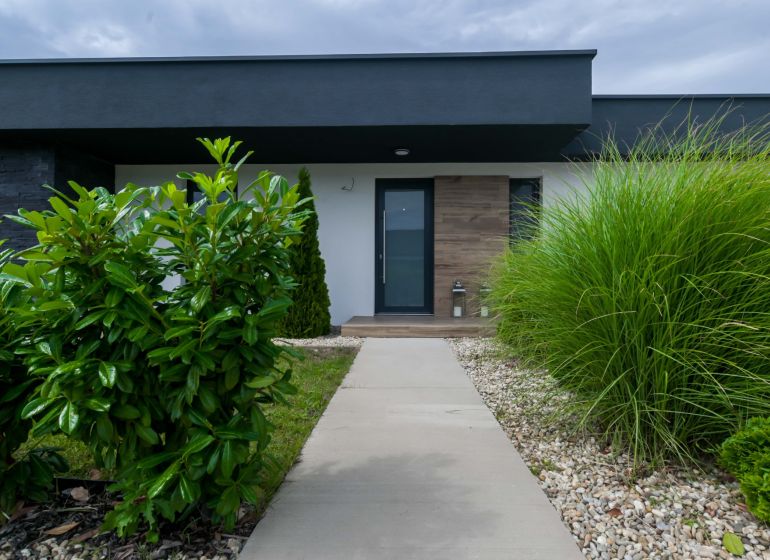 A family house in Košúty with a garden, a walkway, and modern shrubs in the front part.