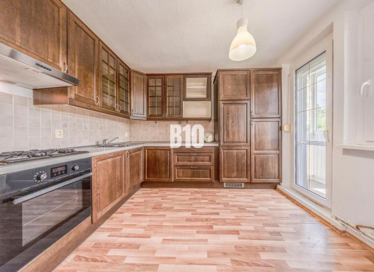 A kitchen in a 2-room apartment with a wooden decor and balcony doors.