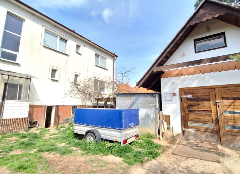 A family house on Štúrova Street in Ludanice with wooden garage doors and a trailer.