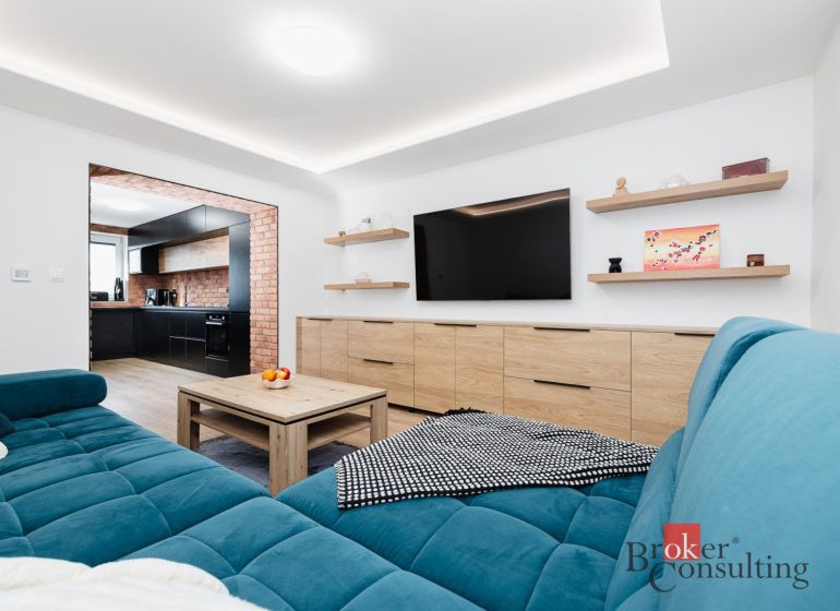 Living room with wood-patterned flooring and a blue sofa in a two-room apartment.