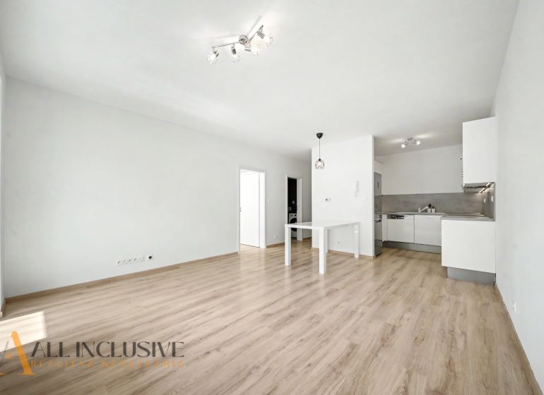 Living room in a 2-room apartment with a kitchen and a wooden decor floor.