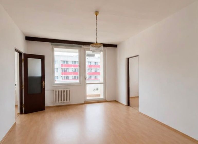A spacious room with a wooden decor floor and two windows in a 3-room apartment.