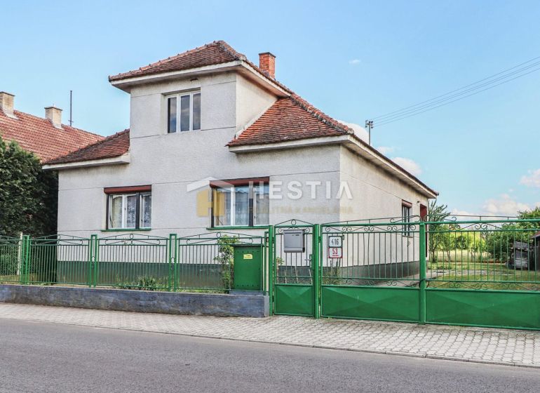 A family house in Borský Mikuláš with white walls and a green fence.