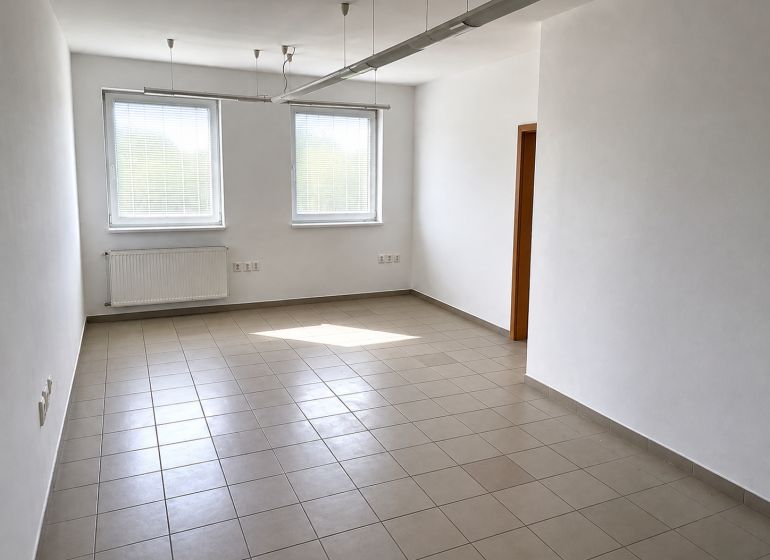 Spacious office with tiles, white walls, and two windows.