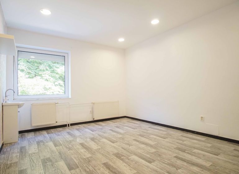 An office with a large window and a wooden decor floor.