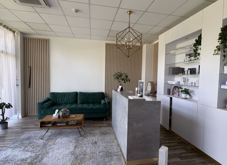 Commercial premises with a wood-patterned floor, a reception desk, and a green sofa.
