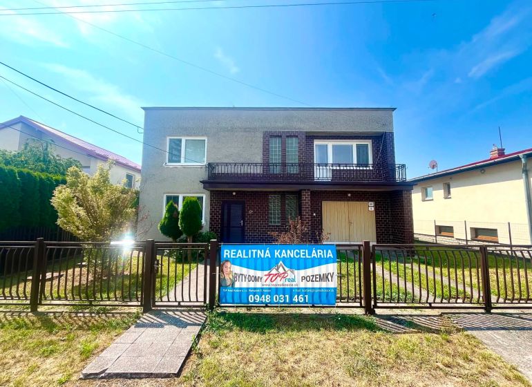 A family house on Agátová Street in Čaňa with a front garden and a real estate agency banner.