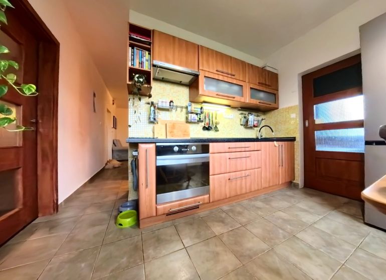 A kitchen in a 4-room apartment with tiles and a wooden decor kitchen unit.