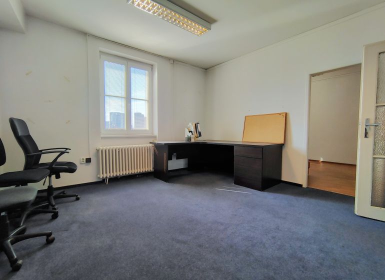 Offices with blue carpet, simply furnished, with a desk and chairs.