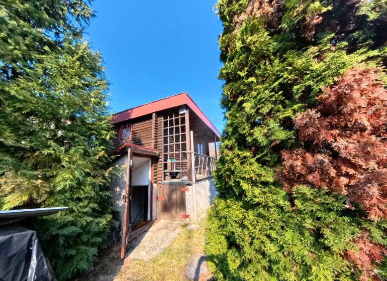 A cottage in Štitáre on Pri Kaplnke street surrounded by trees and a blue sky.
