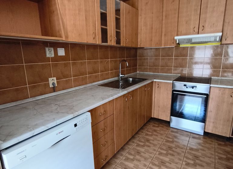 A kitchen with wooden decor in a 3-room apartment, equipped with appliances and cabinets.