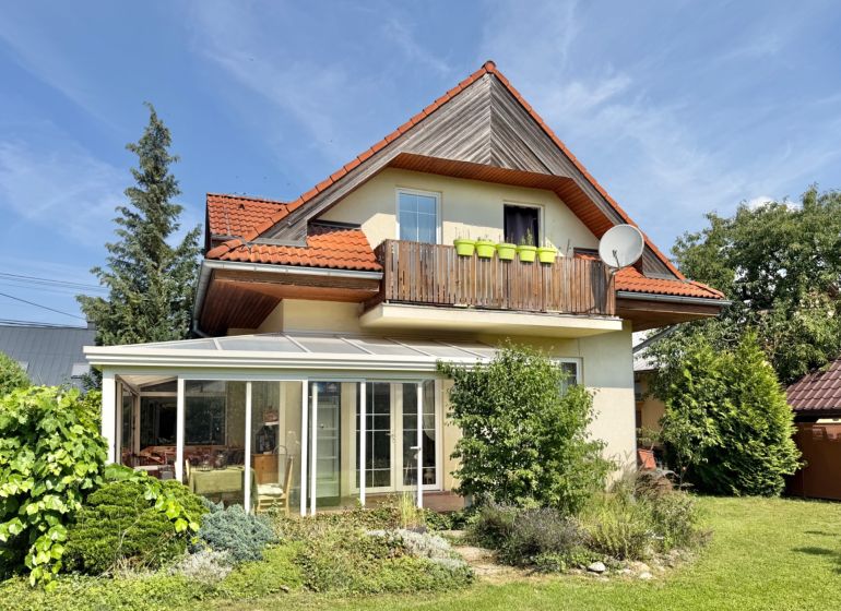 A family house in Mojš with a balcony, a glassed-in veranda, and a well-maintained garden.