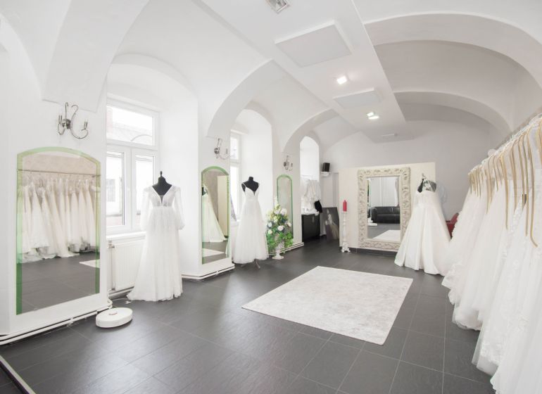 Commercial space with luxury wedding dresses and large mirrors, elegant lighting fixtures.
