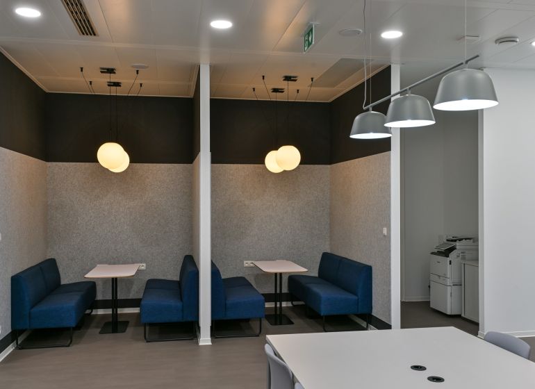 Offices with conference tables, blue sofas, and pendant lights for comfortable meetings.