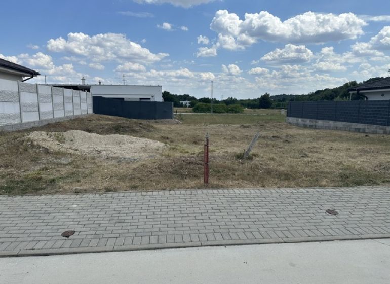Residential plots in Lučenec, an empty building plot between houses, blue sky.